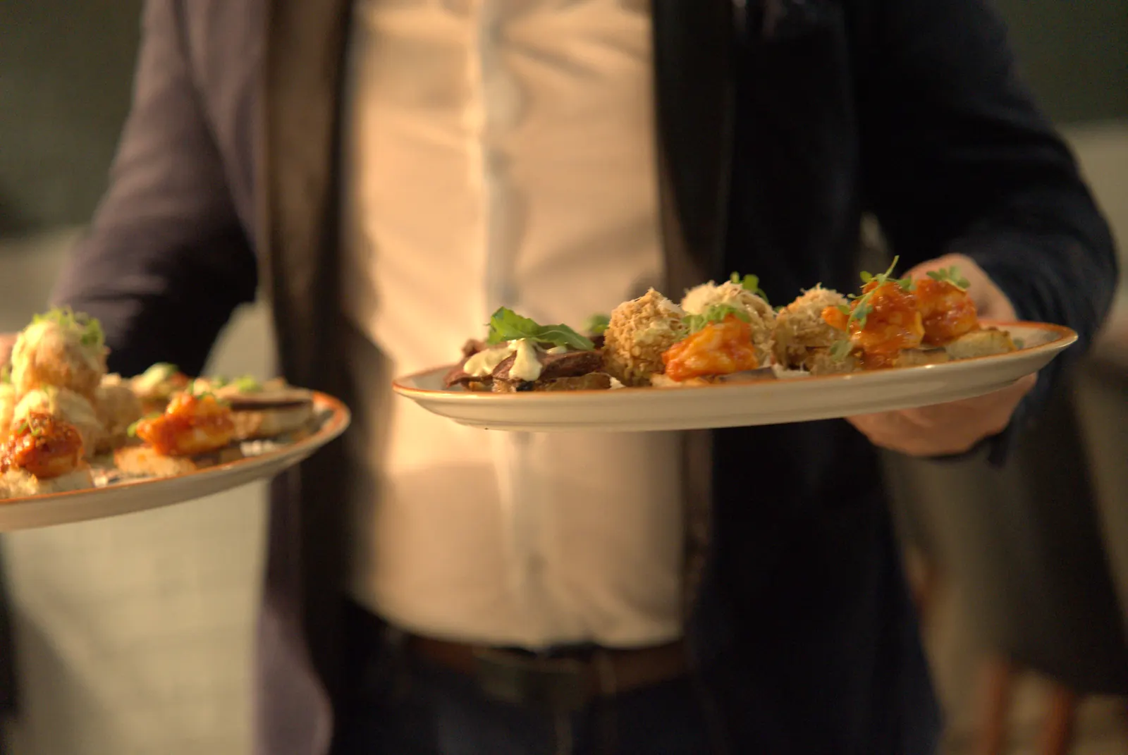 A server carrying two platters of festive canapés
